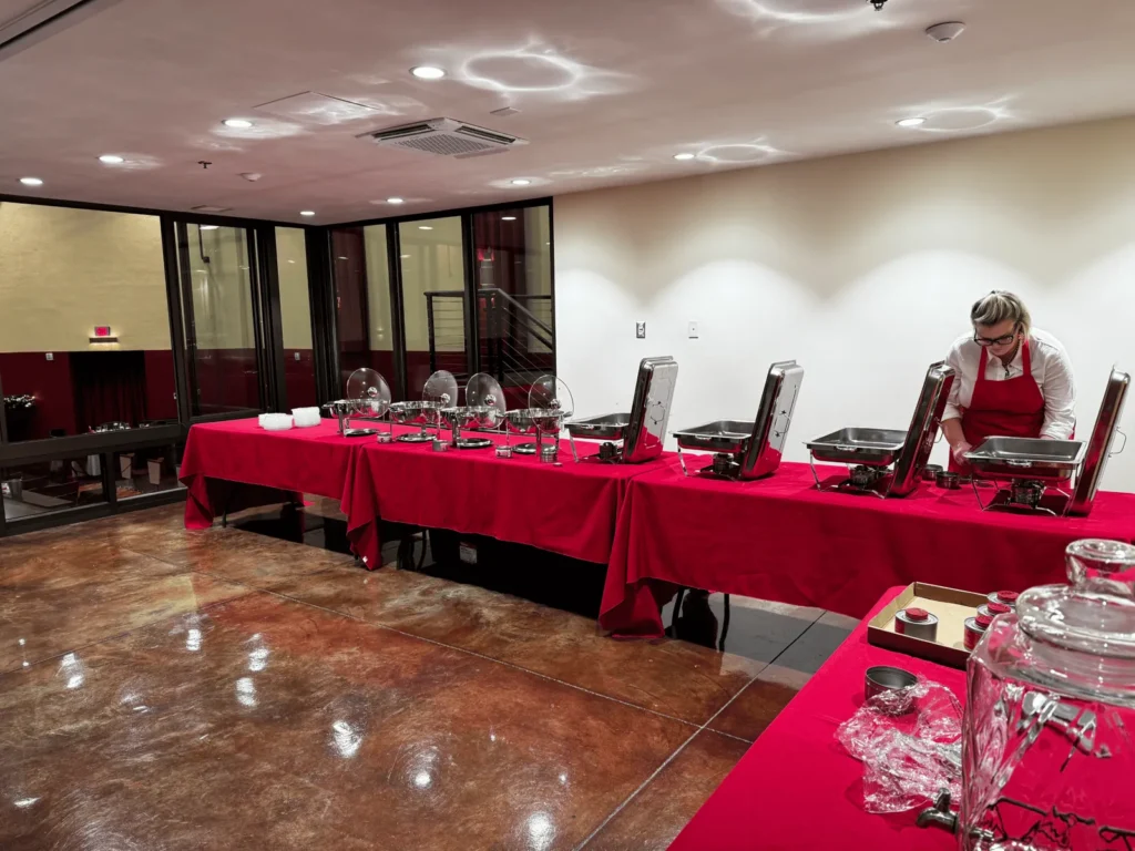 A buffet laid out on red tablecloths in a glass-walled room