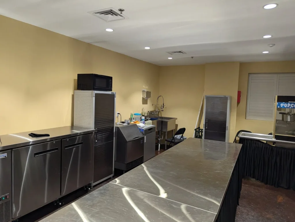 The concessions area: steel counters, a refrigerator and a popcorn sign