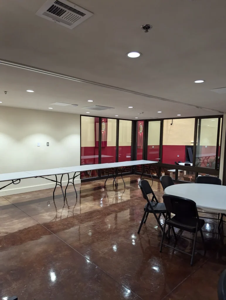 A meeting room with a polished floor, folding tables and chairs