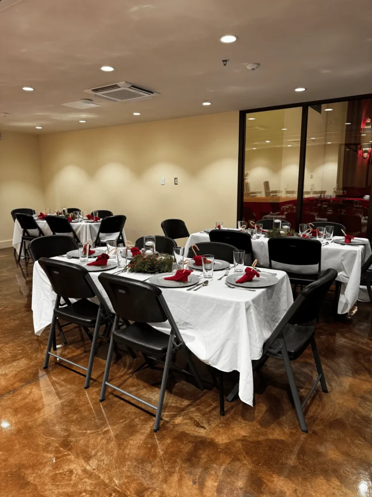 Round tables with white cloths in a room with glass walls