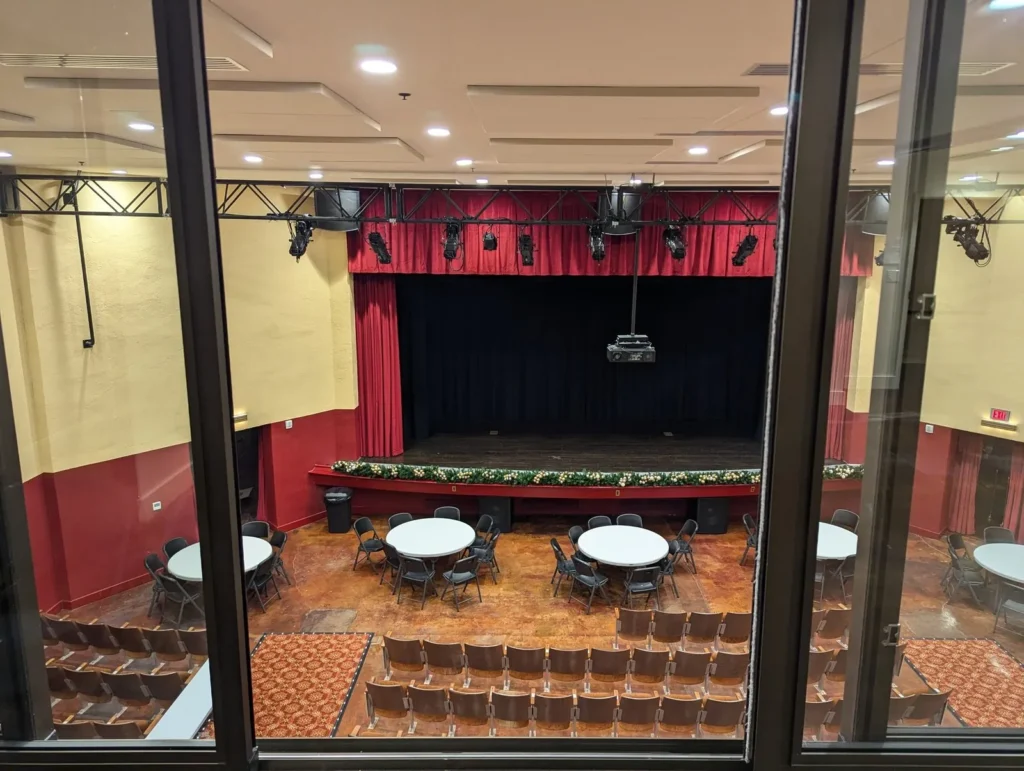 The stage and round tables in the auditorium, seen through the glass wall of an upstairs room