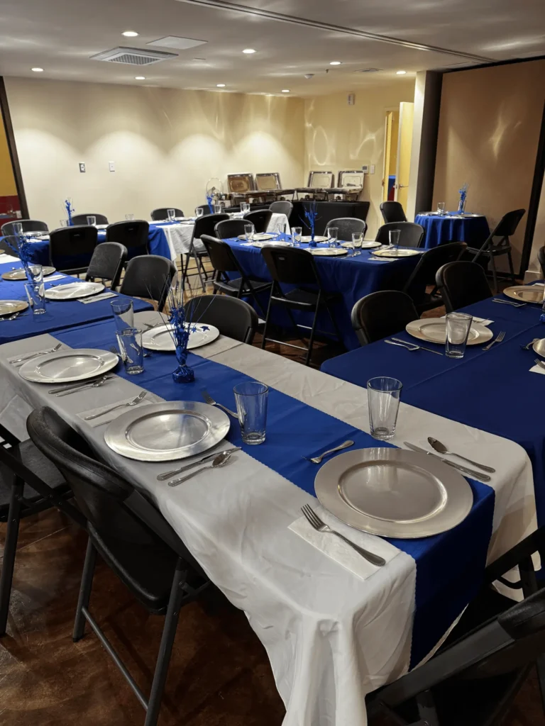 Long tables with blue runners and white cloths, set for a dinner