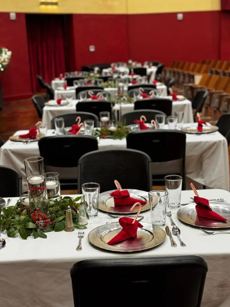 Tables laid with white cloths, red napkins and greenery