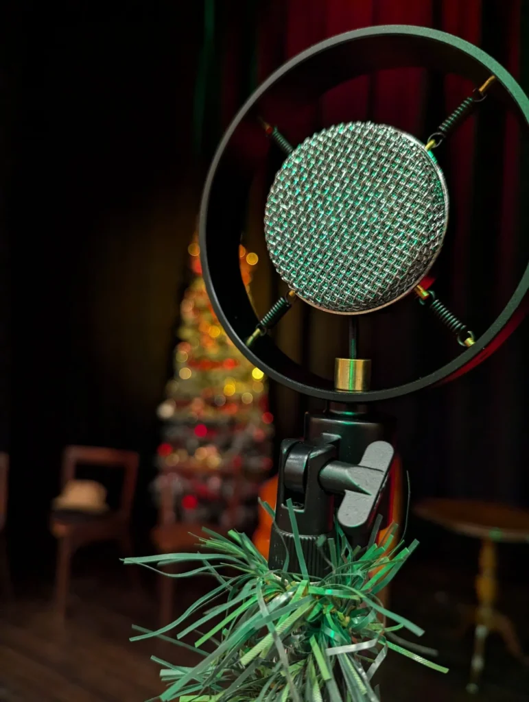 A vintage-style microphone on stage in front of a lit Christmas tree